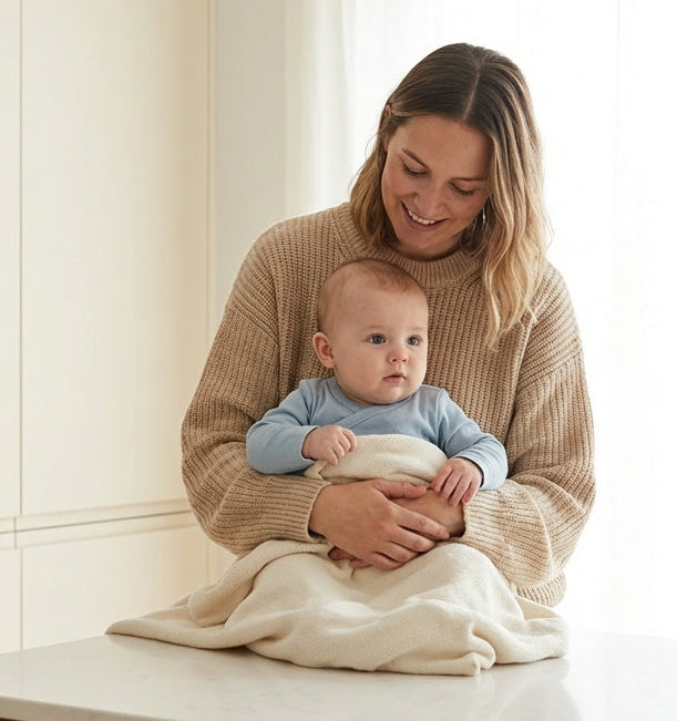 Woman holding a baby in a kitchen with a Pantone color swatch.